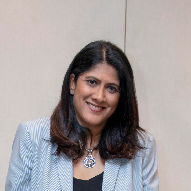 Woman wearing a light gray blazer against a beige background